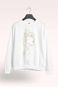 سويت شيرت نسائي أبيض مطبوع وجه فني ذهبي، تصميم أنثوي بخامة قطنية ناعمة، يناسب الاستخدام اليومي أو المناسبات غير الرسمية 1 WhatsApp Image 2025 10 18 at 2.55.11 PM 1