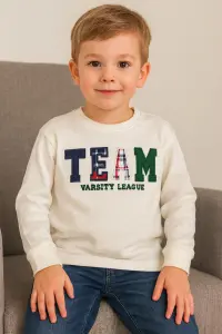 سويت شيرت أولادي أبيض بطبعة "TEAM" مزخرفة، تصميم شبابي كاجوال بروح رياضية 1 WhatsApp Image 2025 10 22 at 3.37.15 PM